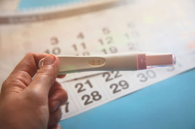 Teste de gravidez positivo segurado por tentante, com duas listrinhas visíveis representando o sonho do positivo após a jornada nos grupos de fertilidade